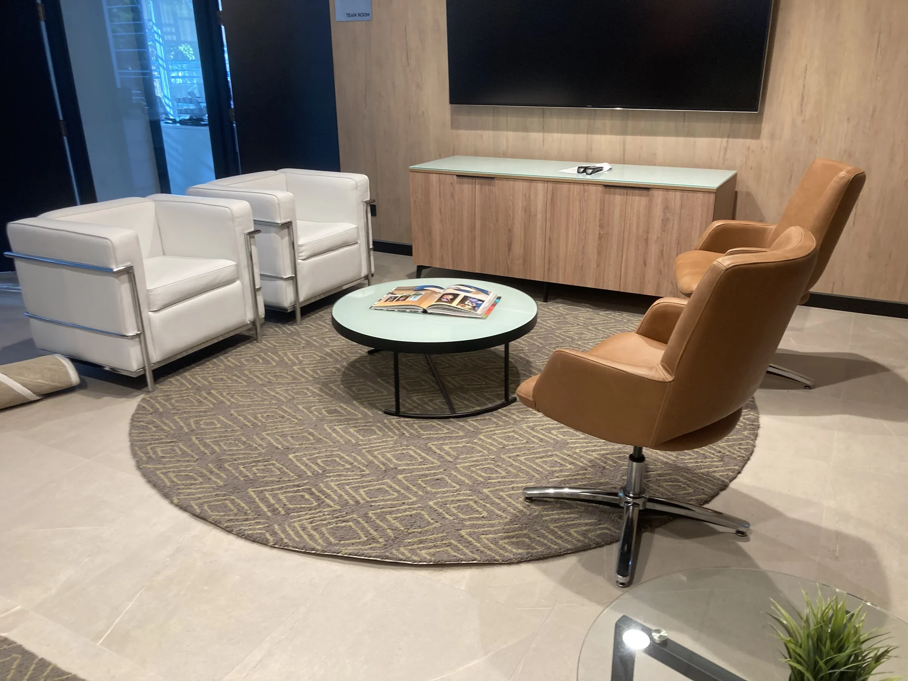 Área de encuentro corporativa con mobiliario de oficina y mueble de madera a medida