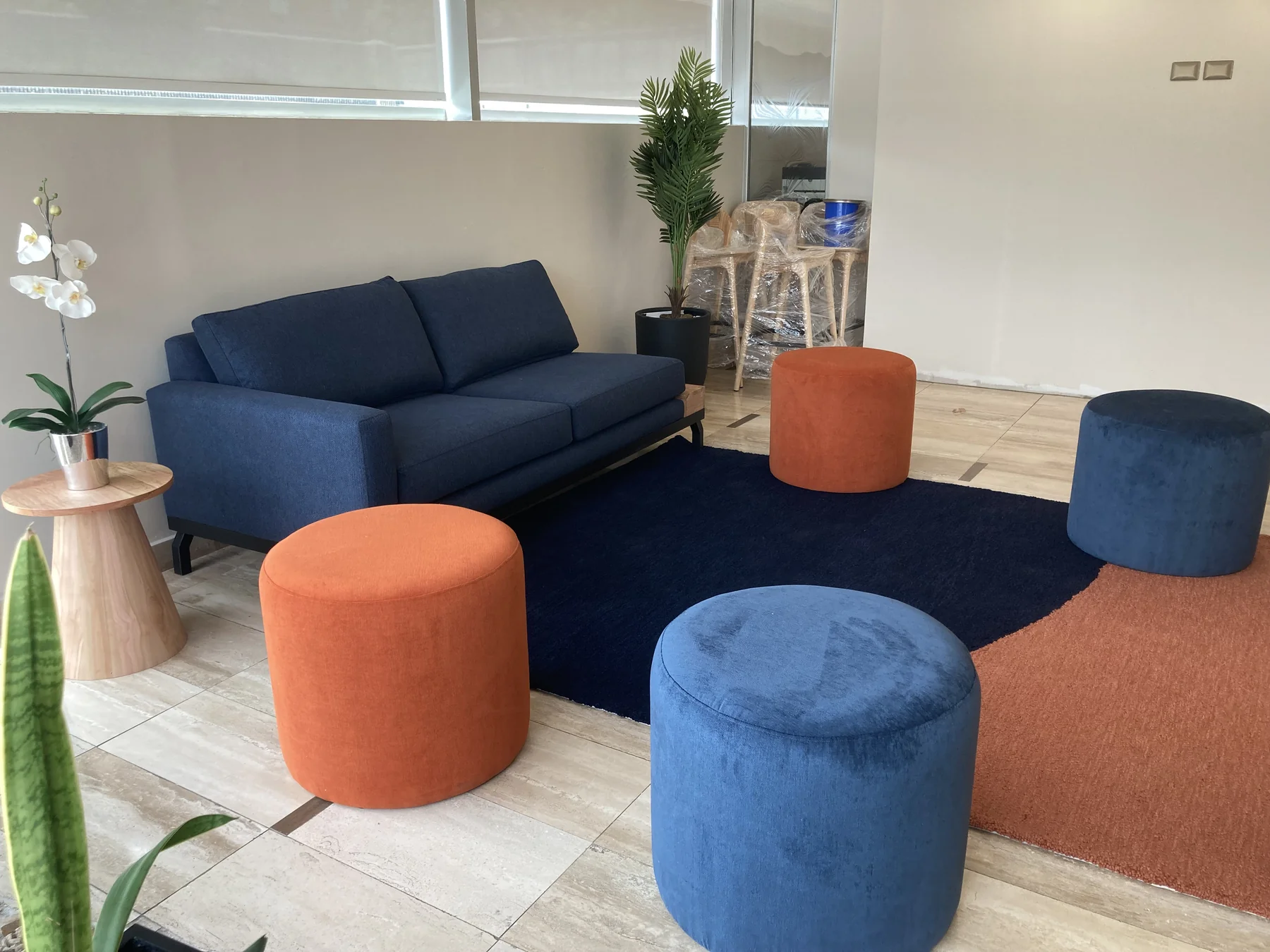 Zona colaborativa de oficina con sofá y asientos modulares azules y naranjos