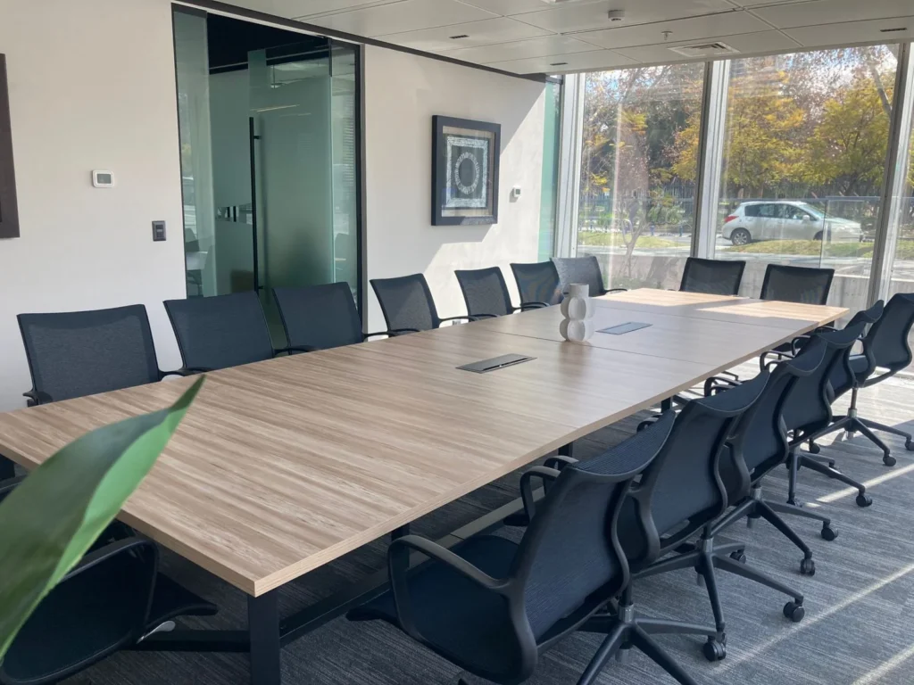 Sala de reuniones corporativa equipada con mesa de madera y sillas de oficina