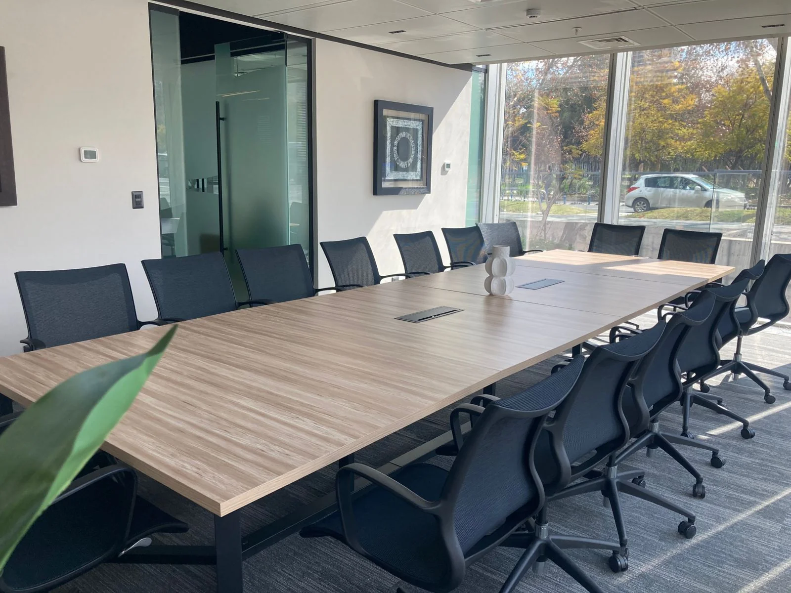 Sala de reuniones corporativa equipada con mesa de madera y sillas de oficina
